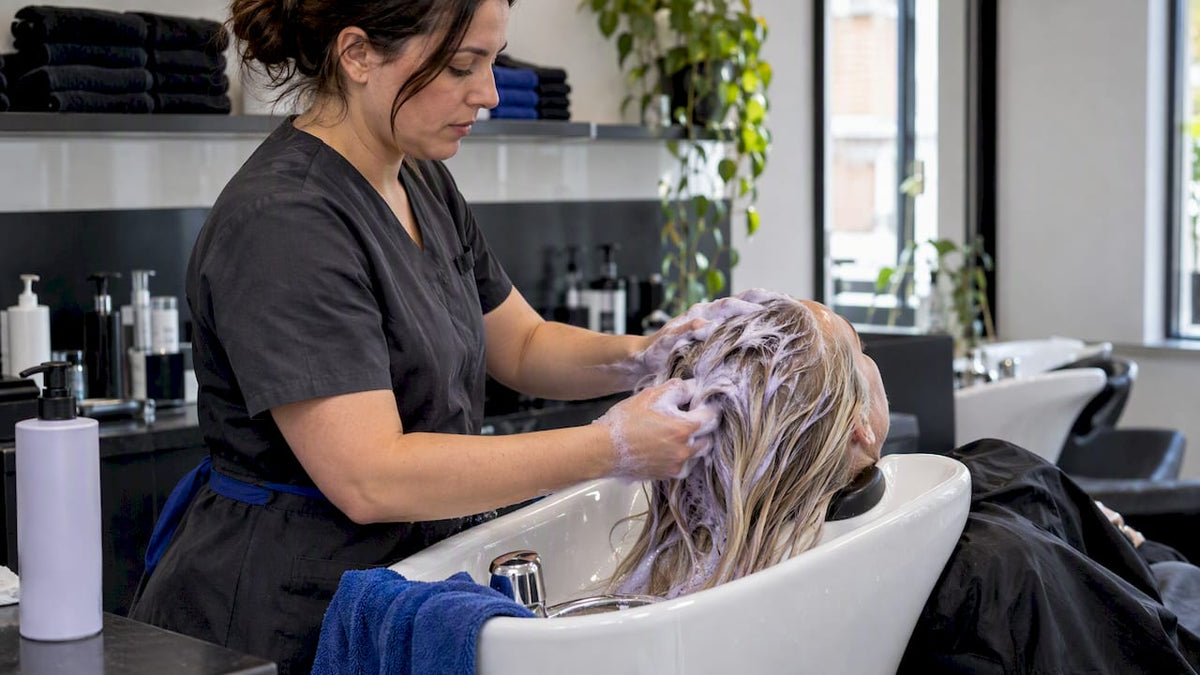 Colourist applying violet shampoo to blonde hair