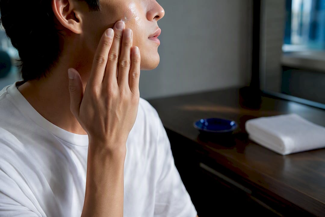 Person applying facial serum in bathroom