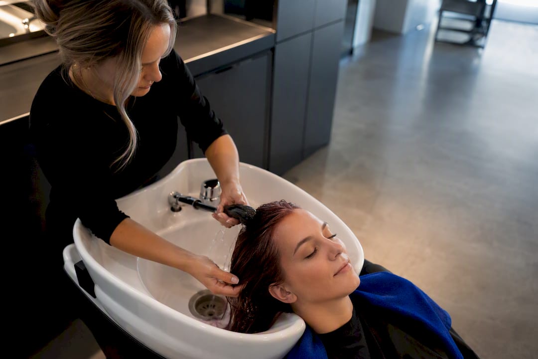 Stylist rinsing freshly coloured hair