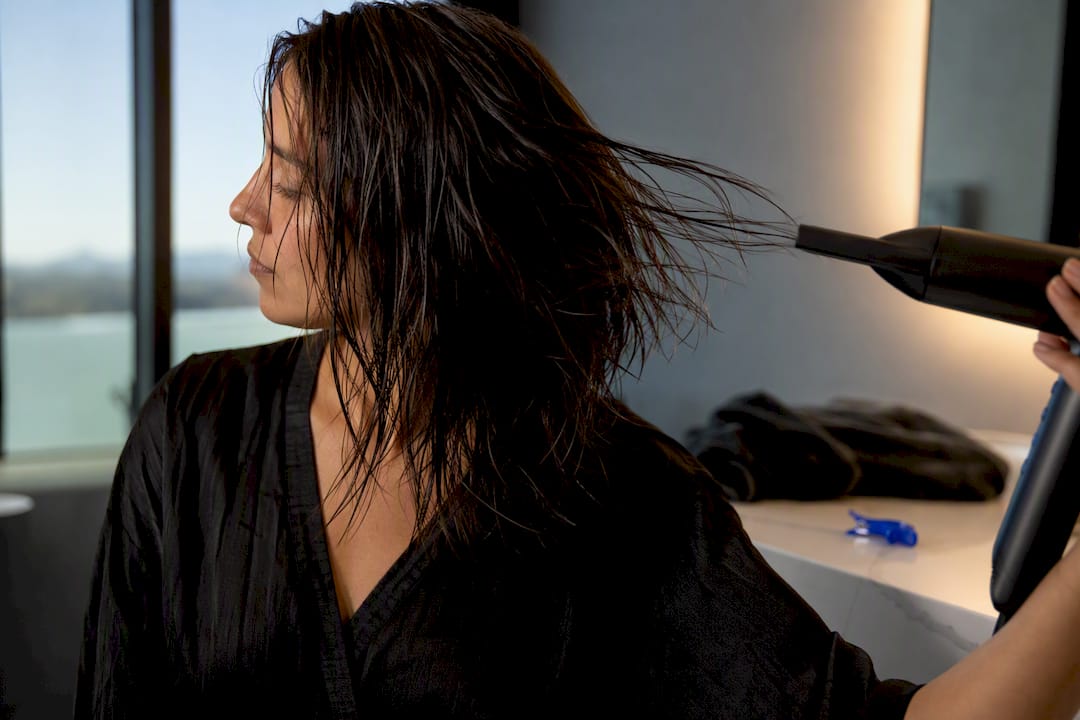 Person drying damp hair at home