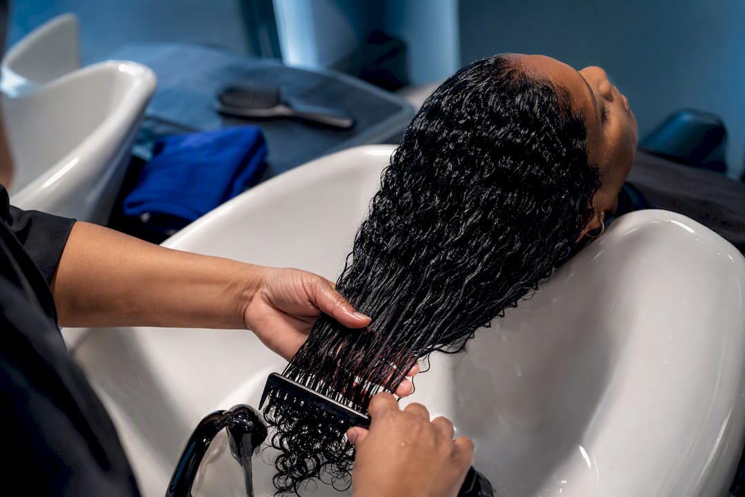 Hands detangling textured hair in salon