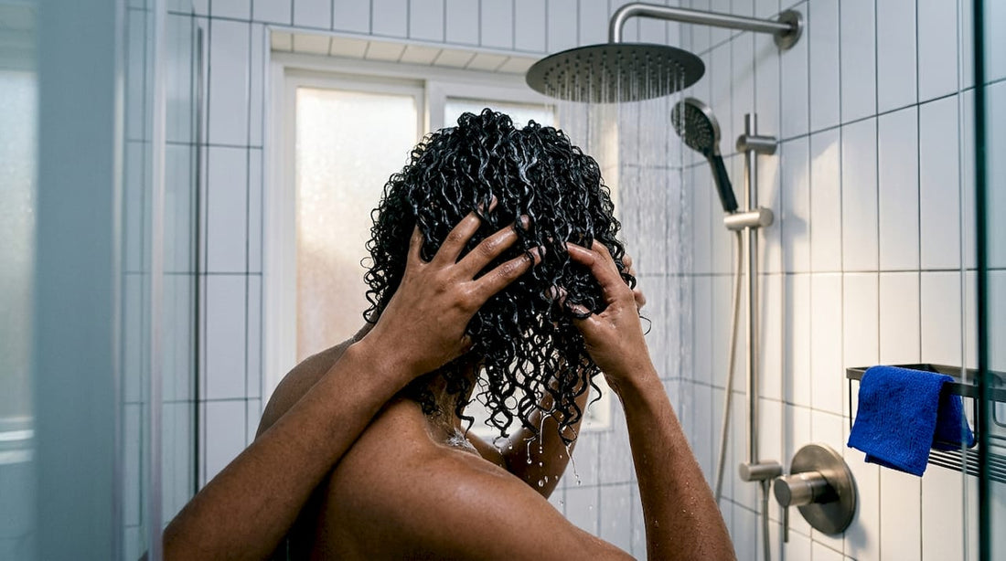 Curly hair being shaped under shower water